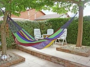 a colorful hammock sitting between two trees with chairs at Cozy Holiday Home in Piquecos with Private Swimming Pool in Piquecos
