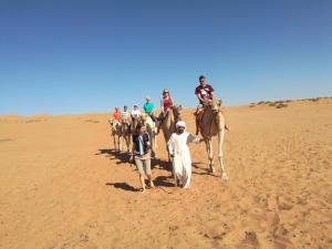 a group of people riding a camel in the desert at Desert Retreat Camp in Al Wāşil