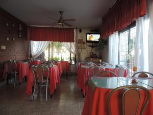 jadalnia z czerwonymi stołami, krzesłami i oknami w obiekcie Hotel Carlos Paz w mieście Villa Carlos Paz