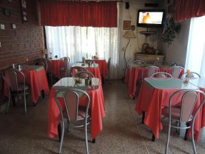 um restaurante com mesas e cadeiras vermelhas e uma televisão em Hotel Carlos Paz em Villa Carlos Paz