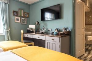 a bedroom with a desk with a television on the wall at City Gate in Exeter
