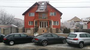 three cars parked in a parking lot in front of a house at Family Pension in Arad