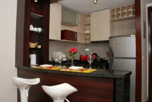 a kitchen with a bar with white chairs and a refrigerator at Puerta Arauco Apartamentos in Santiago