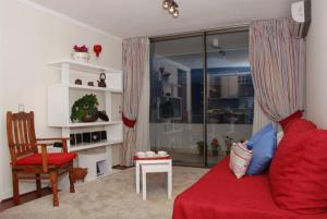sala de estar con sofá rojo y silla en Puerta Arauco Apartamentos, en Santiago
