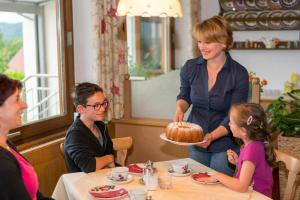 uma mulher a servir um bolo a uma menina numa mesa em Frühstückspension Götzfried-Hof em Millstatt