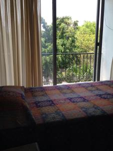 a bedroom with a bed and a large window at Hotel Flamingos Colima in Colima