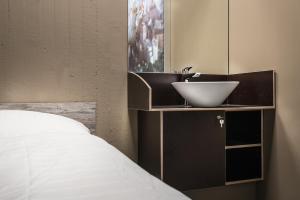 ein Bad mit einem Waschbecken und einem Bett in der Unterkunft BoxHotel Göttingen (App Based Hotel) in Göttingen