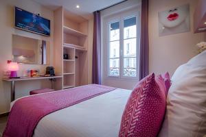 Un dormitorio con una cama con almohadas rosas y una ventana en Pink Hotel, en París