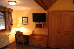 Zimmer mit einem Schreibtisch, einem TV und einem Stuhl in der Unterkunft Steiner Wirt in Tiefenbach
