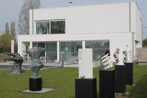 un bâtiment avec des sculptures exposées devant lui dans l'établissement B&B Het Museum, à Berlaar