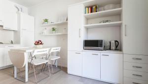 eine Küche mit weißen Schränken sowie einem Tisch und Stühlen in der Unterkunft Italianway-Bligny 19 in Mailand