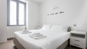 ein weißes Schlafzimmer mit einem weißen Bett und Handtüchern darauf in der Unterkunft Italianway-Bligny 19 in Mailand
