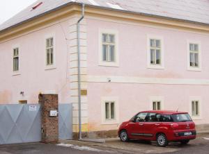 a red car parked in front of a pink building at Apartmány u komína in Terezín