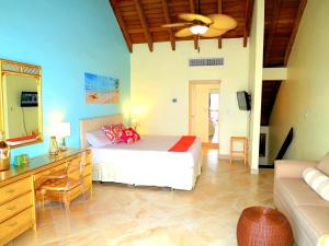 a bedroom with a bed and a desk and a couch at Luxury Beachfront Duplex Villa on Sapphire Beach IV in Frydendal