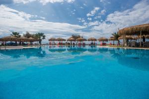a large swimming pool with umbrellas and the ocean at Plaza Beach Hotel in Plaka