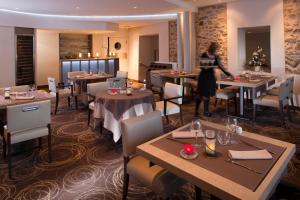 a woman standing in a restaurant with tables and chairs at Logis Le Relais Saint Jacques in Saint-Léonard-de-Noblat