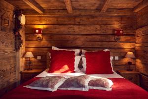 ein Bett mit roten Kissen in einem Schlafzimmer aus Holz in der Unterkunft Hôtel Le Manoir des Montagnes in Les Rousses