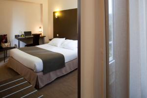 a bedroom with a bed and a desk with a laptop at Logis Le Relais Saint Jacques in Saint-Léonard-de-Noblat