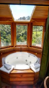 een groot bad in een kamer met 2 ramen bij Chalés de Analuz in Visconde De Maua