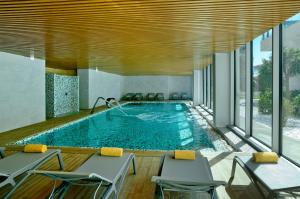 a pool in a hotel with chairs and a swimming pool at Alisios in Albufeira