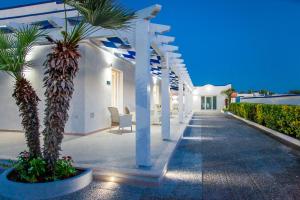 a white house with palm trees and a pathway at Blu d'aMare B&B in Porto Cesareo