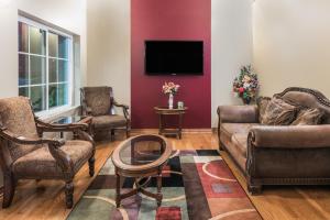 a living room with a couch and chairs and a tv at Super 8 by Wyndham Fort Worth North in Fort Worth