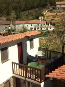 einen Balkon eines Hauses mit Stühlen und einem Tisch in der Unterkunft Casas da Encosta in Proença-a-Nova