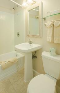 a bathroom with a sink and a toilet and a mirror at Surfcomber On The Ocean in South Yarmouth