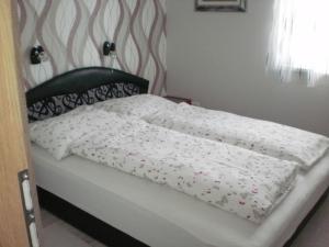 a bed with a white comforter on it at Molni in Balatonfůzfő