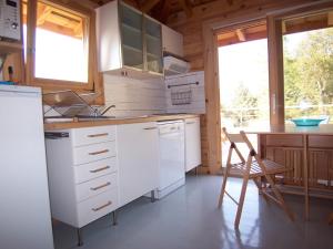 a kitchen with white cabinets and a table and a chair at Albaria Lodge in Saint-Florent