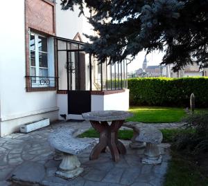 einen Steintisch und zwei Bänke vor einem Gebäude in der Unterkunft Le Repos du Marinier in Gien