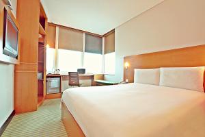 ibis Kuwait Salmiya في الكويت: غرفه فندقيه سرير كبير وتلفزيون