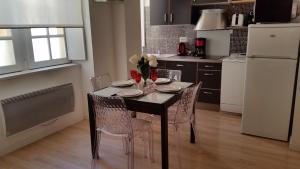 a kitchen with a table with chairs and a white refrigerator at LES TROIS CHANDELIERS un petit paradis en plein centre ville in Bordeaux