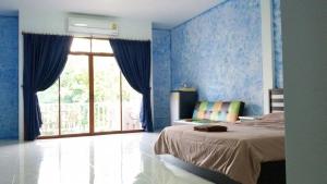 a bedroom with blue walls and a bed and a window at Da Puccio Rawai Guesthouse in Rawai Beach