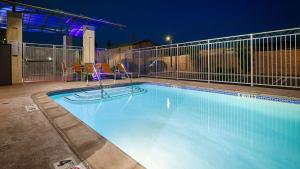 einen Pool in der Nacht mit zwei Stühlen und einem Tisch in der Unterkunft Best Western Plus Gardena-Los Angeles Inn & Suites in Gardena