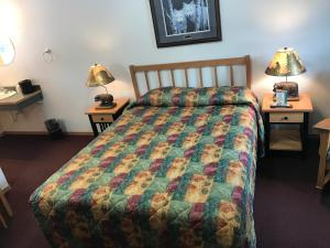 Harborview Inn في سيوارد: غرفة فندقية بها سرير وطاولتين بها مصابيح