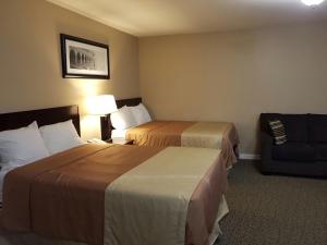 una habitación de hotel con 2 camas y una silla en Sunrise Motel en Regina