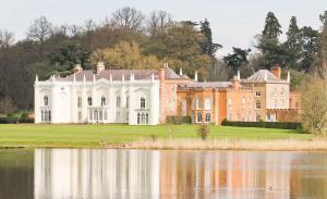 una casa grande con un estanque frente a ella en The North Wing - Combermere Abbey en Whitchurch