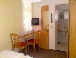 Zimmer mit einem Bad mit einem Waschbecken und einem Tisch in der Unterkunft Pension Am Klünderberg in Binz