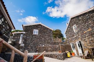 una casa de piedra con una valla delante de ella en Stone Dreams - Adega, en Calheta de Nesquim