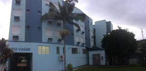 a building with a palm tree in front of it at Hotel Tourist Araranguá in Araranguá