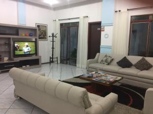 sala de estar con 2 sofás y TV en Hotel Tourist Araranguá, en Araranguá