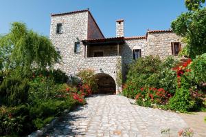 a stone house with a stone pathway and flowers at Elise Cottage in Vathi