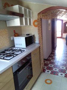 eine Küche mit Herd und Mikrowelle in der Unterkunft Holiday Home Recanati in Giardini-Naxos