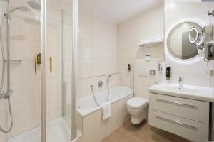 ein weißes Bad mit einer Dusche, einem WC und einem Waschbecken in der Unterkunft Naam Apartment Frankfurt Hotel City-Airport in Frankfurt am Main