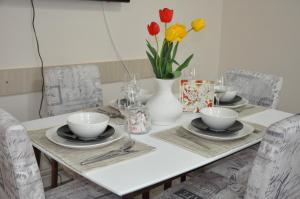a dining room table with a white vase with red and yellow flowers at Aria apartmani in Vrdnik