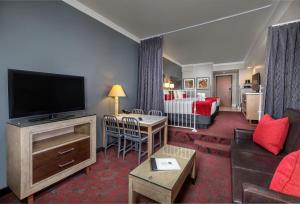 a living room with a television and a room with a bed at Desert Palms Hotel & Suites Anaheim Resort in Anaheim