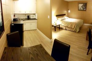 a small room with a bed and a kitchen with a microwave at Above Tide Motel in Campbell River
