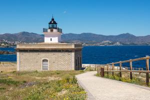 a lighthouse sitting on top of a hill next to the ocean at Acogedor apartamento en el centro de Llançà in Llança