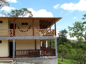 dom z balkonem i drzewami w tle w obiekcie Hospedaje y Camping Buena Vista w mieście San Agustín